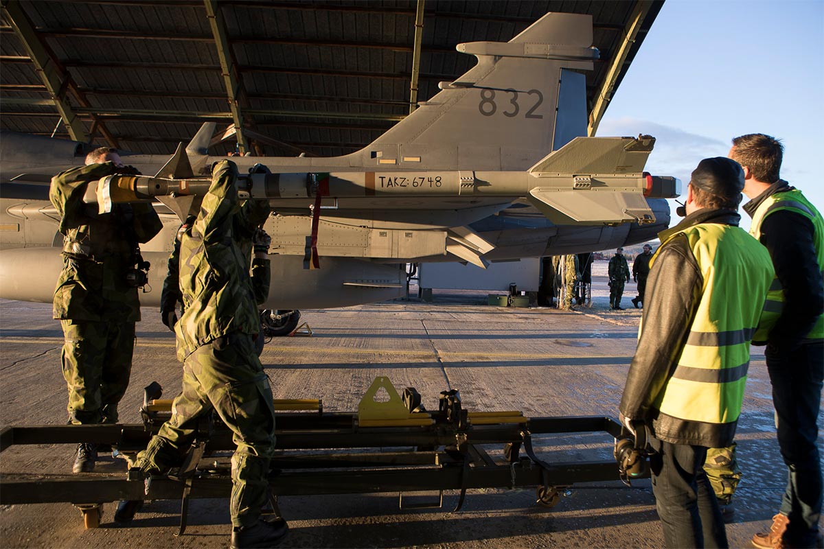 Four persons inspecting a LaGS missile on a fighter aircraft before take-off