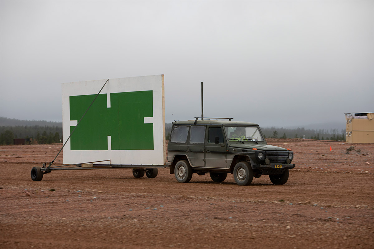 A SUV with a large shield in tow as remotely controlled moving target