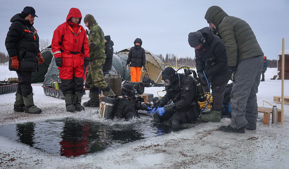 DIvers around an ice-free stretch of water, preparing for diving