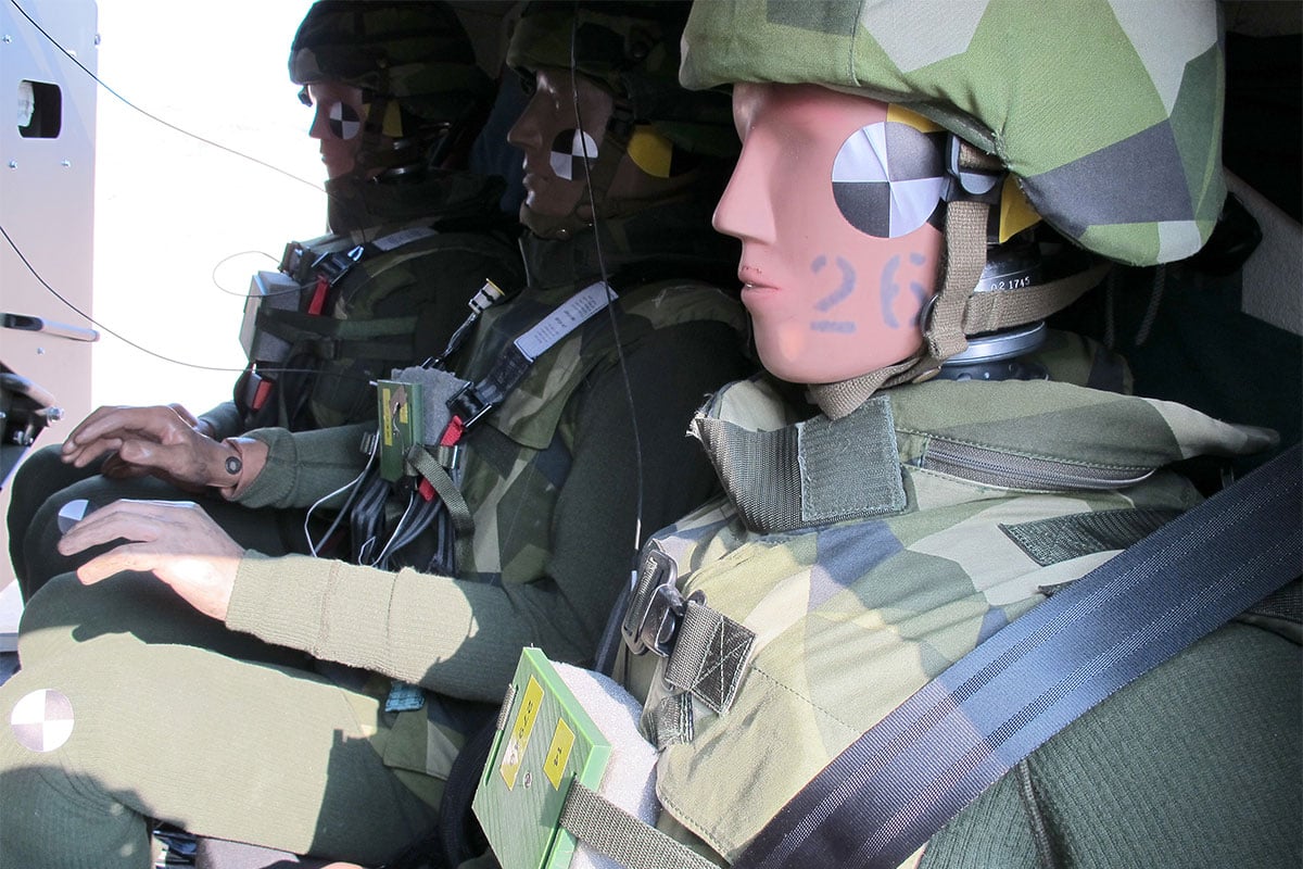 Three instrumented dummies in green battledress placed in a vehicle for survivability testing 